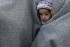 Stranded Refugees from Syria are covered with blankets while waiting to be allowed to cross the Greek-Macedonian border near the northern Greek village of Idomeni, Sunday, Feb. 28, 2016. About 5,500 migrants are braving rainy weather at a tent camp close to the border and another 500 are camped at a gas station 17 kilometers away.
