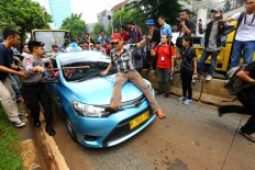 The Police and some officers were protecting a Taxi  from the drivers protest at Senayan, South Jakarta, Tuesday (03/22/2016). Thousands of Jakarta taxi drivers protest against ride-hailing app During the action they demanded the closure of application service company like Uber, Grab and Gojek. Their presence are illegal as transportation public operating because they have no license as it and have contributed to the decrease of the conventional transportation drivers'income .