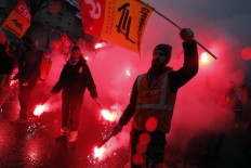 Demonstrators burn flares during a protest in Paris, Thursday, March 31, 2016. Some French train drivers, teachers and others are on strike to reject a government reform relaxing the 35-hour workweek and other labor rules. AP/Christophe Ena