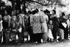 A child stands among women waiting in line for social assistance in Satungal, a badly affected village 7 km from Kathmandu. May 1, 2015. JP/ Ayomi Amindoni