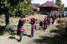 The family walks to the new sites with those carrying the boxes leading the parade. JP/ Hotli Simanjuntak