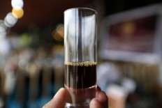 A glass is half filled with extracted coffee ready to be served to coffee lovers. Some say Indonesians add too much sugar to their coffee, detracting from the original coffee flavor. JP/ Hotli Simanjuntak

 