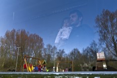 In this Sunday, April 10, 2016 photo, An Afghan refugee holding a child looks outside a window of a room at the former prison of Westlingen in Heerhugowaard northwestern Netherlands.  AP Photo/Muhammed Muheisen
