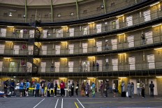 In this Wednesday, April 20, 2016 photo, refugees and migrants line up to receive their lunch at the former prison of De Koepel in Haarlem, Netherlands. With crime declining in the Netherlands, the country is looking at new ways to fill its prisons. The government has let Belgium and Norway put prisoners in its empty cells and now, amid the huge flow of migrants into Europe, several Dutch prisons have been temporarily pressed into service as asylum seeker centers. AP Photo/Muhammed Muheisen