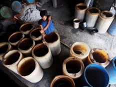 A worker checks on the fermented sugarcane juice ahead of distillation. JP/ Ganug Nugroho Adi
