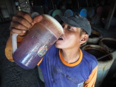 A worker stays hydrated while working inside the warm room. JP/ Ganug Nugroho Adi



