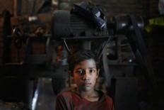 Bangladeshi boy Robin,10, looks towards camera as he works at a factory that makes metal utensils in Dhaka, Bangladesh, Sunday, June 12, 2016. He earns less than $5 per week. AP Photo/ A.M. Ahad