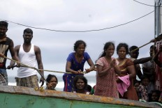The stranded asylum seekers gesture for help. They are not allowed to leave the boat as they lack passports and immigration documents. The Jakarta Post/ Hotli Simanjuntak