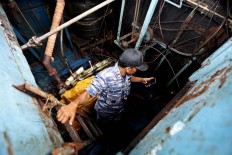 An officer checks the engine of the stranded boat. The Jakarta Post/Hotli Simanjuntak