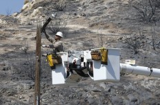 Robert Delgado, a lineman for Southern California Edison, works on power line at fire ravaged South Lake, Calif., Monday, June 27, 2016. Power crews work restore power to the area that was swept by fire near Lake Isabella, Calif. The fire that started Thursday, has taken the lives of an elderly couple, apparently overcome by smoke, burned more than 70 square miles, and is 40 percent contained. AP Photo/Rich Pedroncelli