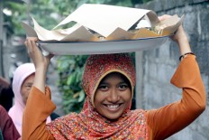 A village resident carries a tumpeng plate on her head before Megibung starts. JP/Zul Trio Anggono