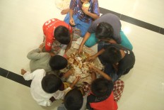 Children sit in a circle to eat nasi tumpeng [cone-shaped yellow rice] during the Megibung event at the Muhajirin Mosque in Kepaon Muslim village in Denpasar, Bali, on June 15.  JP/Zul Tri Anggono