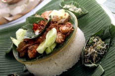 Variations of the nasi tumpeng [cone-shaped yellow rice] dish include fried chicken, vegetables and chili paste. JP/Zul Trio Anggono