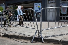 Pedestrians walking in the Greenwich Village neighborhood of Manhattan are seen behind police barricades walking past a poster in honor of the victims of the shooting in Orlando, Saturday, June 25, 2016 in New York. AP Photo/Mary Altaffer