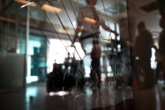 A traveler passes a broken windows at the arrivals hall at Ataturk Airport, Wednesday, June 29, 2016. AP Photo/Bram Janssen