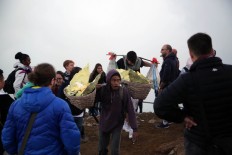 A traditional sulfur miner is seen carrying baskets filled with sulfur rocks amid foreign tourists on Mount Ijen. JP/P J Leo