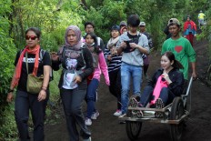 A female tourist from Thailand is uses the trolley service offered by a traditional sulfur miner on Mount Ijen. JP/P J Leo
