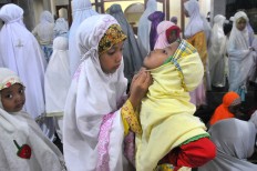 A young female student tidies her friend's mukena, or prayer clothes, before the Quran recital starts. JP/Ganug Nugroho Adi