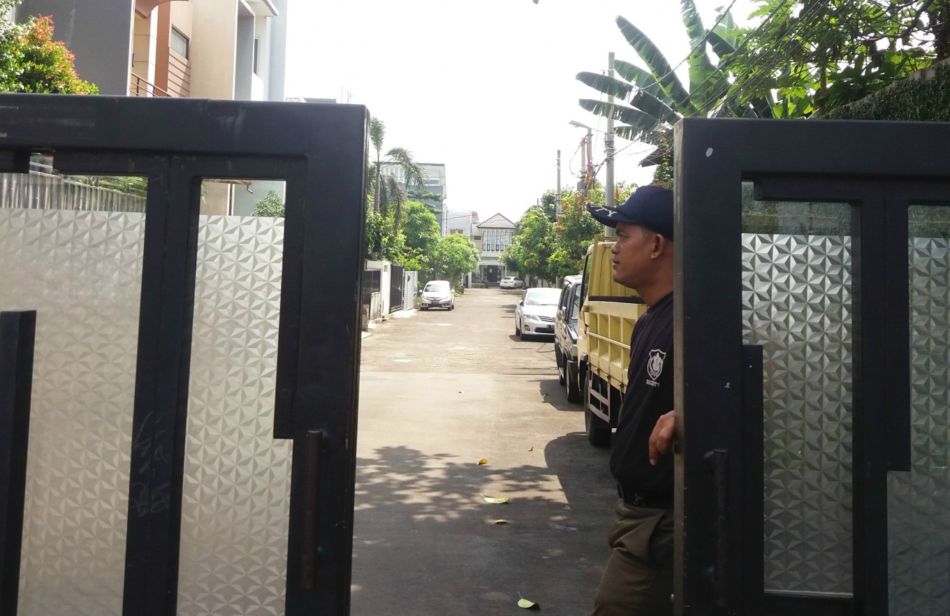 A security guard, dressed in the old navy blue outfit, stands at the gate of a housing complex located in Palmerah, West Jakarta, in July 2016. After asking security guards to change their uniforms to resemble those of police officers, the National Police are planning to change them once again so they will not look too similar.