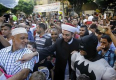 A Lebanese cleric and an entertainer dressed in a Batman suit exchange greetings after Eid al-Fitr prayers that mark the end of the Muslim fasting month of Ramadan, in the southern port city of Sidon, Lebanon, Wednesday, July 6, 2016. AP Photo/Mohammed Zaatari
