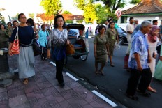 Queen Hemas of the Yogyakarta Kingdom [on sidewalk, right], accompanied by her daughter Princess Mangkubumi, walks to Alun Alun Utara [North square] of Yogyakarta to join Idul Fitri prayers with other common folk. JP/ Wienda Parwitasari