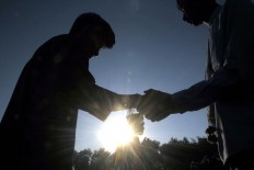 Two men shake hands after Idul Fitri prayers at Sudirman Square, Denpasar, Bali, on Wednesday. Millions of Muslims in Indonesia celebrate the festivities by asking for people’s forgiveness after 30 days of dawn-to-dusk fasting during Ramadhan this year. JP/ Zul Trio Anggono