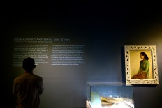 A visitor reads text on the wall beside a painting by Indonesia's first president Sukarno. The Jakarta Post/Wienda Parwitasari
