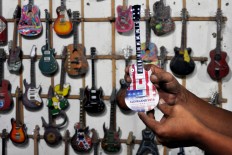 A Gibson Les Paul miniature is displayed. In the background are samples of past work. JP/ Albertus Magnus Kus Hendratmo
