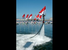 A member of the South Sulawesi Water Ski and Motor Boats Association carries an Indonesian flag while riding a flyboard on Losari Beach, Makassar, South Sulawesi. JP/Andi Hajramurni