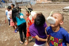 Children of evicted families on Jl. Stasiun Barat in Bandung take part in a cracker­ eating contest during Independence Day celebrations on the site of their former homes on
Wednesday. Psychology students volunteered to organize the celebration for the children, whose homes were demolished by state railway company PT KAI, recently. JP/Arya Dipa