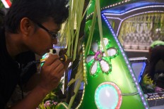 Aan works on lighting decoration on the body of the car for the carnival. JP/ Aditya Sagita