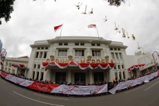 People stand waiting in front of the Merdeka Building for carnival participants to pass by in their colorful costumes in Bandung on Aug. 14. The building was the venue of the Asia-Africa Conference in 1955. JP/Arya Dipa