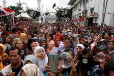 Thousands of people crowd Jl. Asia Africa in Bandung to see and take pictures of the carnival on Sunday, Aug. 14. JP/Arya Dipa