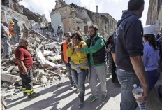 A woman is comforted as she walks through rubble after an earthquake, in Amatrice, central Italy, Wednesday, Aug. 24, 2016. A devastating earthquake rocked central Italy early Wednesday, collapsing homes on top of residents as they slept. At least 23 people were reported dead in three hard-hit towns where rescue crews raced to dig survivors out of the rubble, but the toll was expected to rise as crews reached homes in more remote hamlets. AP Photo/Alessandra Tarantino
