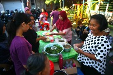 Residents share food provided by their neighbors. JP/Aditya Sagita