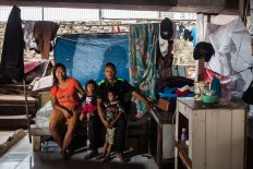 Couple Jony, 29, and Fitri, 24, and their children, Bima, 5, and Kaila, 3, in their home in Pejagalan. They have been living under the toll road since 2008. He worked as a parking attendant before but now he watches and guards trucks that park in the area in exchange for some money. JP/Seto Wardhana