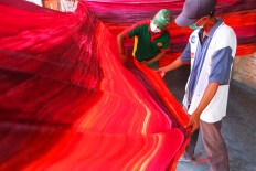 Two workers check on the result of a batik of a contemporary motifs painted with natural dye. This kind of batik get exported to America, Brunei Darussalam, and European countries. JP/Ganug Nugroho Adi