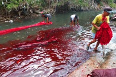 Workers wash batik cloths in a river. Waste from naturally dyed batik is less polluting than batik which uses chemical dyes. JP/Ganug Nugroho Adi