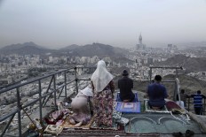 Chechens pray atop of Noor Mountain, where Prophet Muhammad received his first revelation from God to preach Islam, as Egyptians at right watch the view, on the outskirts of Mecca, Saudi Arabia, Friday, Sept. 9, 2016. Muslim pilgrims have begun arriving at the holiest sites in Islam ahead of the annual hajj pilgrimage in Saudi Arabia. The Mecca Royal Clock Tower Hotel is seen at center. AP Photo/Nariman El-Mofty