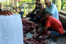 Several men slice meat to be distributed for poor people in Poowo Village of Bone Bolango regency, Gorontalo, on Sept. 12. Besides mosques and open fields, the slaughtering process was also conducted in several residential houses for this year's Idul Adha. JP/Syamsul Huda M. Suhari