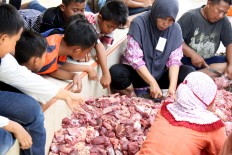 Children look on as piles of meat are sliced into pieces by the Idul Adha qurban committee. The meat was distributed to local people for the Idul Adha celebration at Al Ikhwan Mosque in Medan, North Sumatra, on Sept. 12. JP/Apriadi Gunawan
