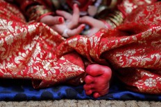 A Nepalese girl, wearing traditional attire with her feet dipped in vermillion paste, waits for Kumari puja to start at the Hanuman Dhoka temple, in Kathmandu, Nepal, Wednesday, Sept. 14, 2016.  AP Photo/Niranjan Shrestha