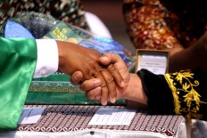 A groom shakes the hand of a penghulu [Islamic wedding vow administrator] at a mass wedding in Tugu Station of Yogyakarta on the morning of Sept. 6.JP/ Aditya Sagita