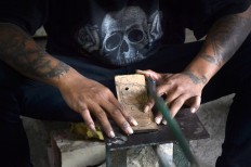 A man cuts a piece of wood following a drawn pattern in a home workshop in Malang East, Java, on Aug. 15. The frames are sold online and the buyers come from Jakarta, Surabaya and even the US and Italy. JP/Aman Rochman