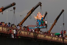 Indian devotees watch as a crane lifts an idol of elephant-headed Hindu god Ganesha to immerse it in river Sabarmati on the final day of the ten-day long Ganesh Chaturthi festival in Ahmadabad, India, Thursday, Sept. 15, 2016. AP Photo/Ajit Solanki
