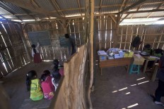 The two classrooms, the one on the left for the lower grades, are divided by wooden planks in the simple structure. JP/ Sigit Pamungkas


