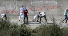 A Kashmiri man ducks to cross an iron barricade with coils of razor wire near a military base at Braripora, near the de facto border dividing Kashmir between India and Pakistan, in Indian controlled Kashmir, Wednesday, Sept. 21, 2016. Kashmir is witnessing the largest protests against Indian rule in recent years, sparked by the July 8 killing of a popular rebel commander by Indian soldiers. The protests, and a sweeping security crackdown, have all but paralyzed life in Indian-controlled Kashmir. AP Photo/Mukhtar Khan


