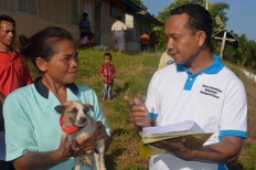 A health officer records data on vaccinated dogs belonging to residents in Kampung Melo on Aug. 31. JP/ Markus Makur
