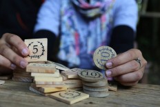 A market administrator shows bamboo coins used for transactions at Papringan Market in Caruban village. JP/Ganug Nugroho Adi