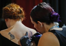 In this picture taken on Sunday, Oct. 16, 2016, a woman gets a tattoo during the International Tattoo Convention Bucharest 2016 in Bucharest, Romania. More than 100 tattoo and piercing artists brought their skills and art to a three-day convention in the Romanian capital. AP Photo/Vadim Ghirda